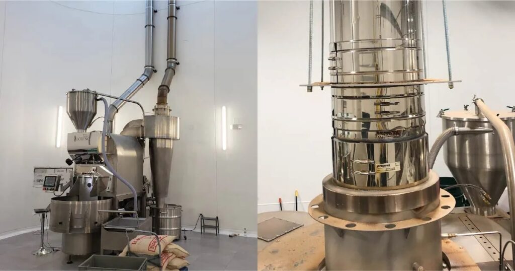 Commercial coffee roaster with stainless steel exhaust ductwork, cyclone chaff collector, and vertical flue stack.